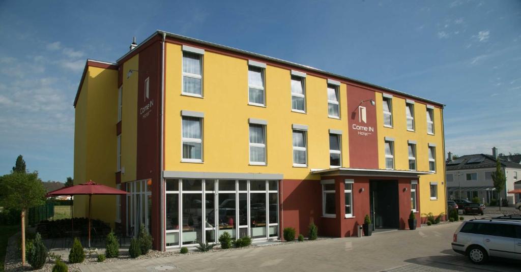 a yellow and red building in a parking lot at Come IN Hotel in Ingolstadt