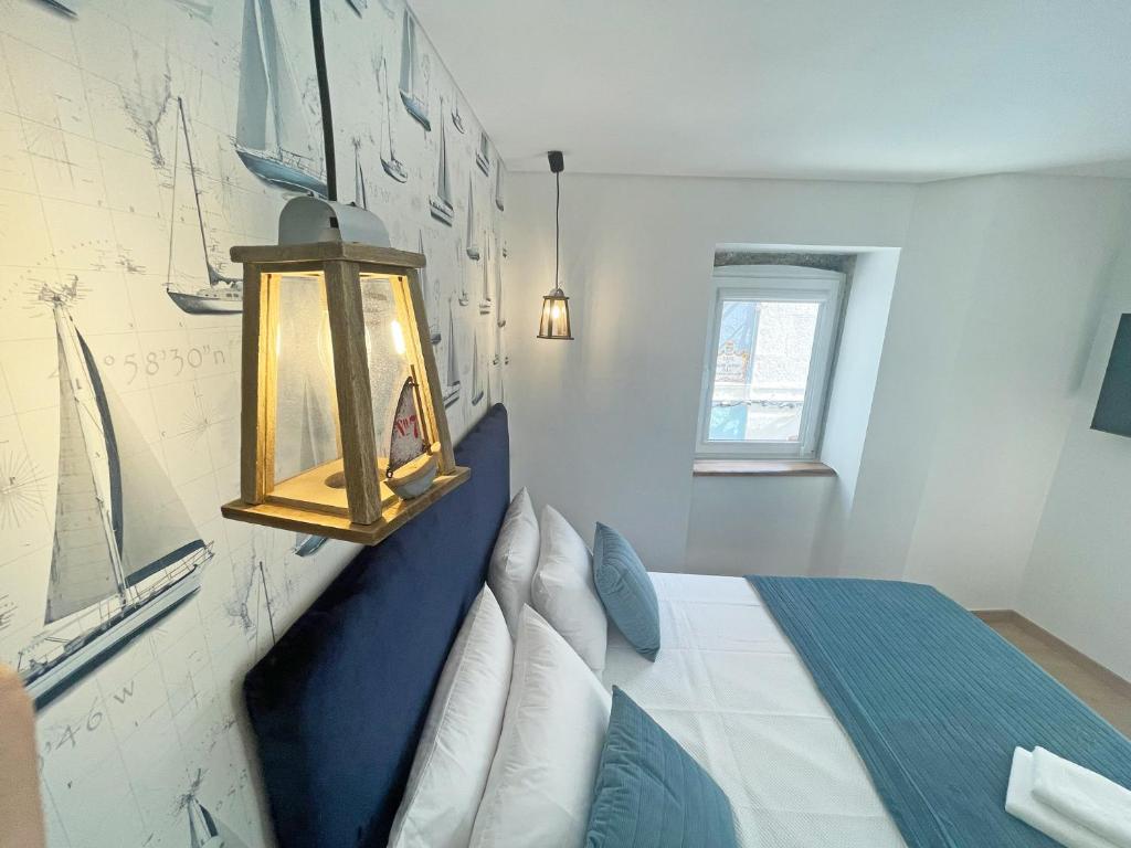 a bedroom with a blue and white bed and a lamp at Baia do Mundo in Setúbal