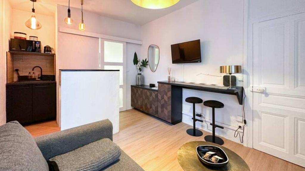 a living room with a couch and a kitchen at Studio Casa Aelys - Quartier des Arènes - Béziers in Béziers