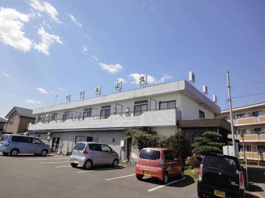 un estacionamiento con autos estacionados frente a un edificio en Hotel Sankyu en Tsukuba