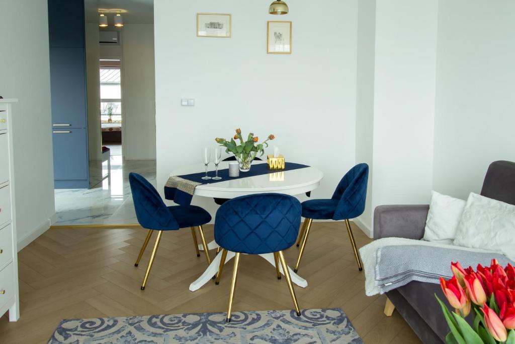 a dining room with blue chairs and a table at Nowy Apartment przy Placu Szembeka in Warsaw