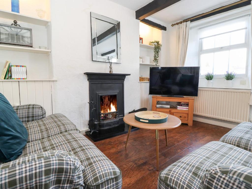 a living room with a fireplace and a tv at Meadow Cottage in Kendal