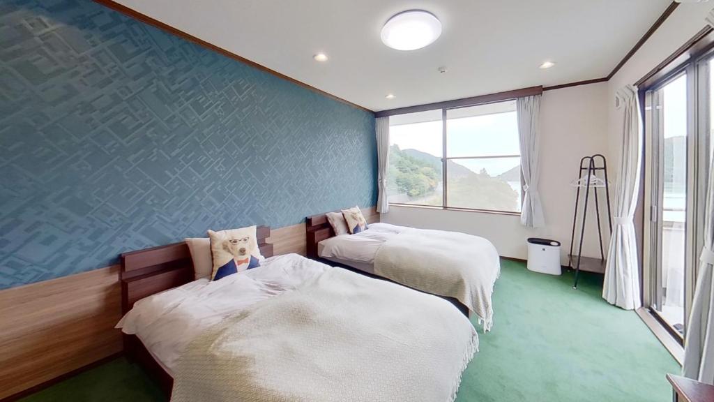 two beds in a room with a blue wall at H,U,B Unzen - Vacation STAY 01672v in Unzen