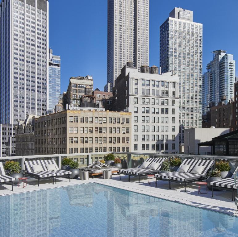 a pool with lounge chairs and a city skyline at Virgin Hotels New York City in New York