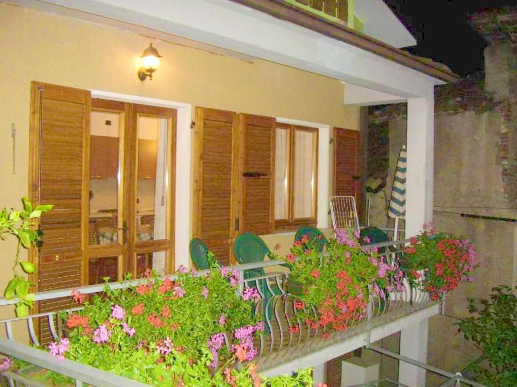 - un balcon avec des chaises et des fleurs dans une maison dans l'établissement 2 bedrooms apartement with furnished balcony and wifi at Prabione 8 km away from the beach, à Campione del Garda