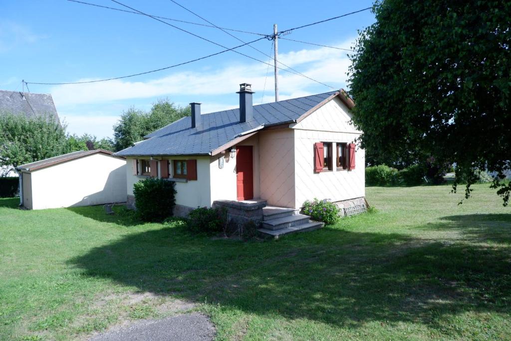 una pequeña casa blanca con una puerta roja en Petit chalet de montagne avec espace extérieur, en Labaroche