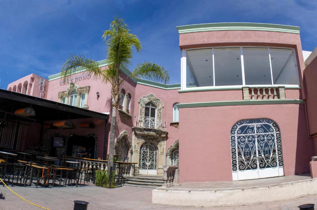 a pink building with a palm tree in front of it at Hotel Gran Domo in León