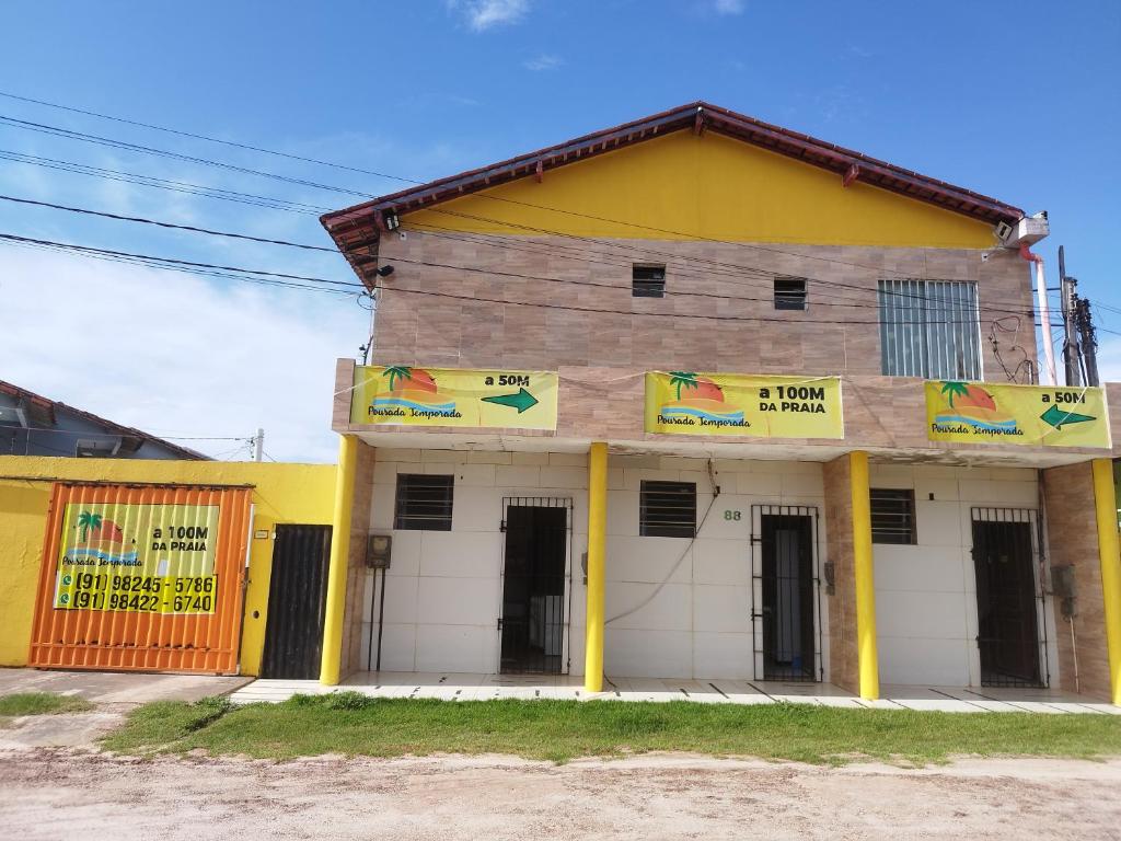 a yellow and white building with a sign on it at Temporada no Atalaia in Salinópolis