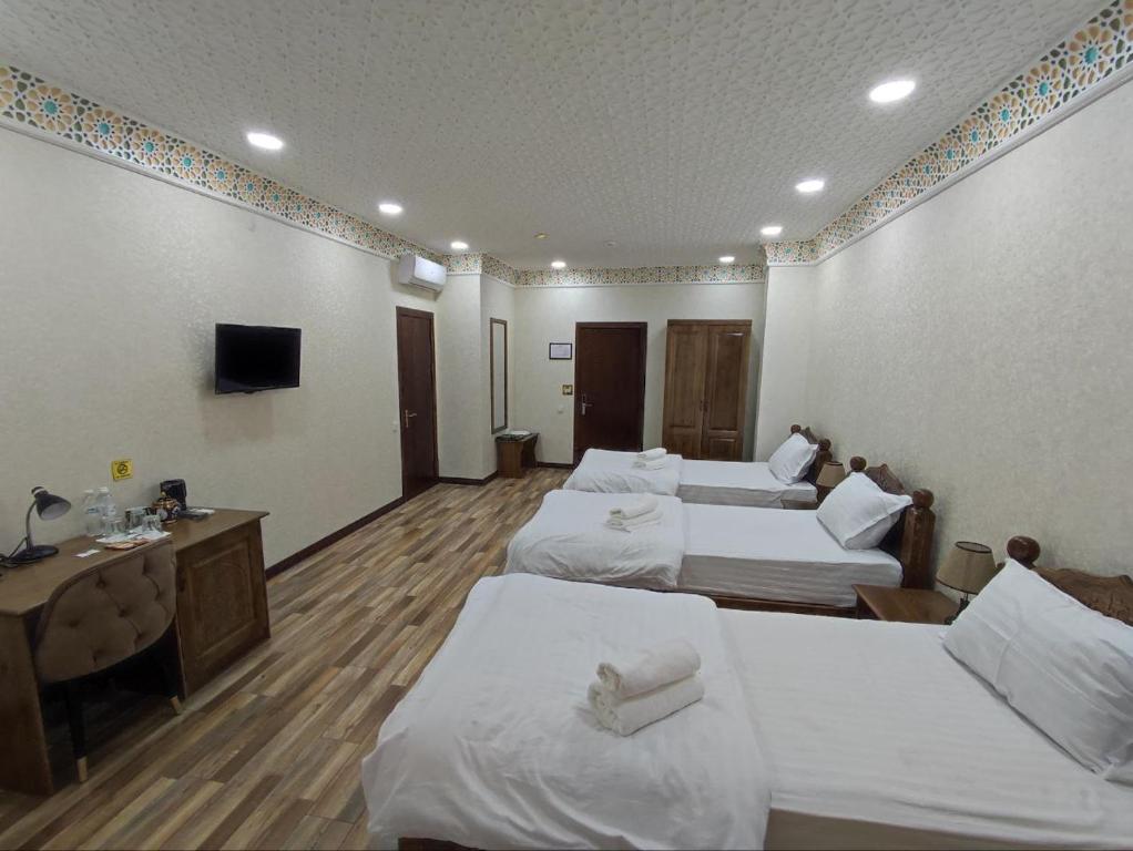 een hotelkamer met drie bedden en een televisie bij Ayvan Plaza hotel in Bukhara