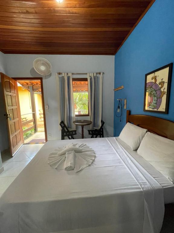 a bedroom with a white bed with a blue wall at Pousada Licuri in Serra do Cipo