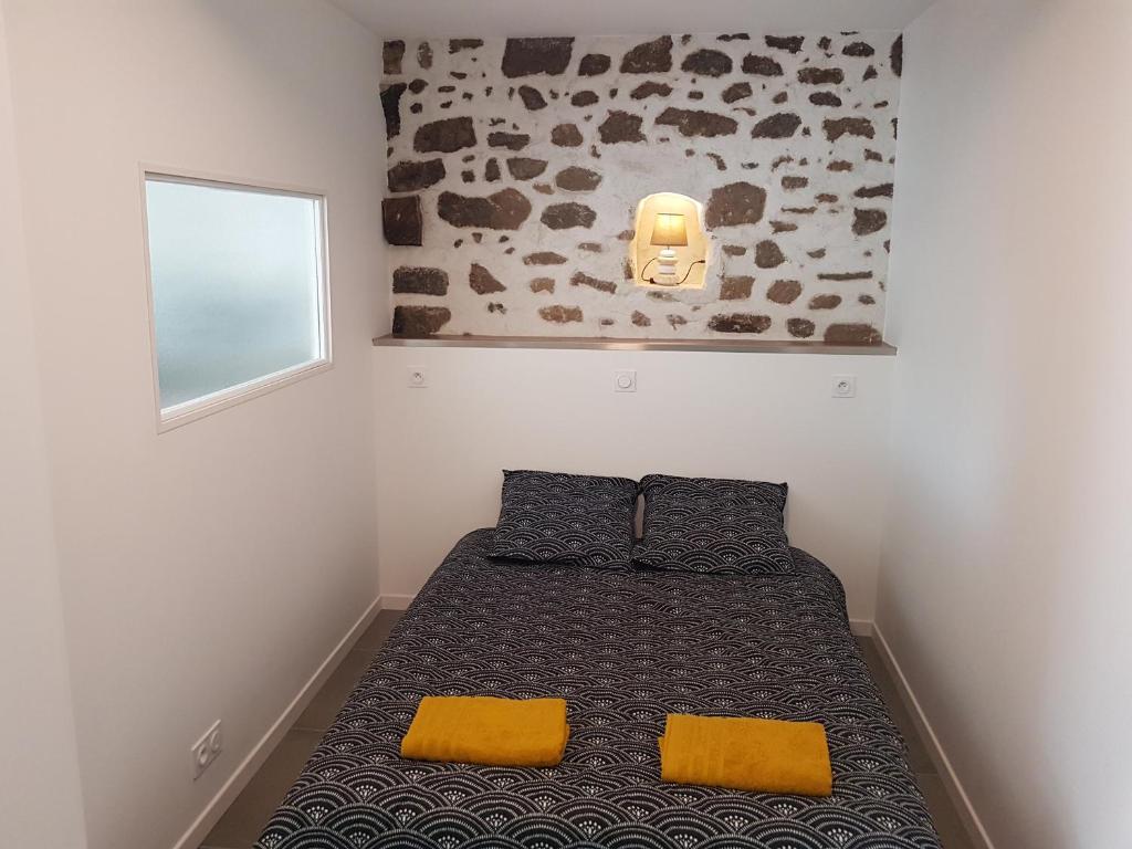 um pequeno quarto com uma cama com almofadas amarelas em Appartement entre Saint-Malo, Dinard, Dinan et Dol em Miniac-Morvan