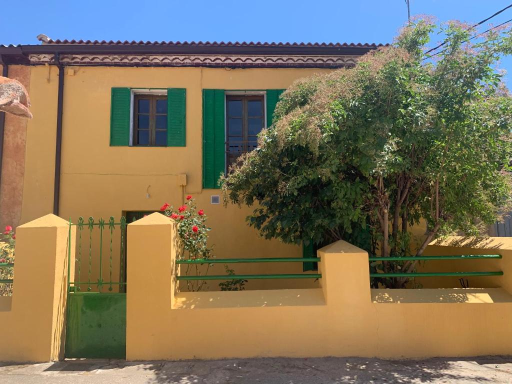 una casa amarilla con una puerta verde y una valla en La Toscana en Lozoya en Alameda del Valle