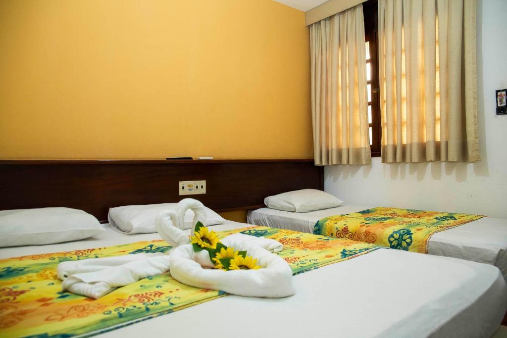 Habitación de hotel con 2 camas, toallas y flores en GB Hoteis Natal, en Natal