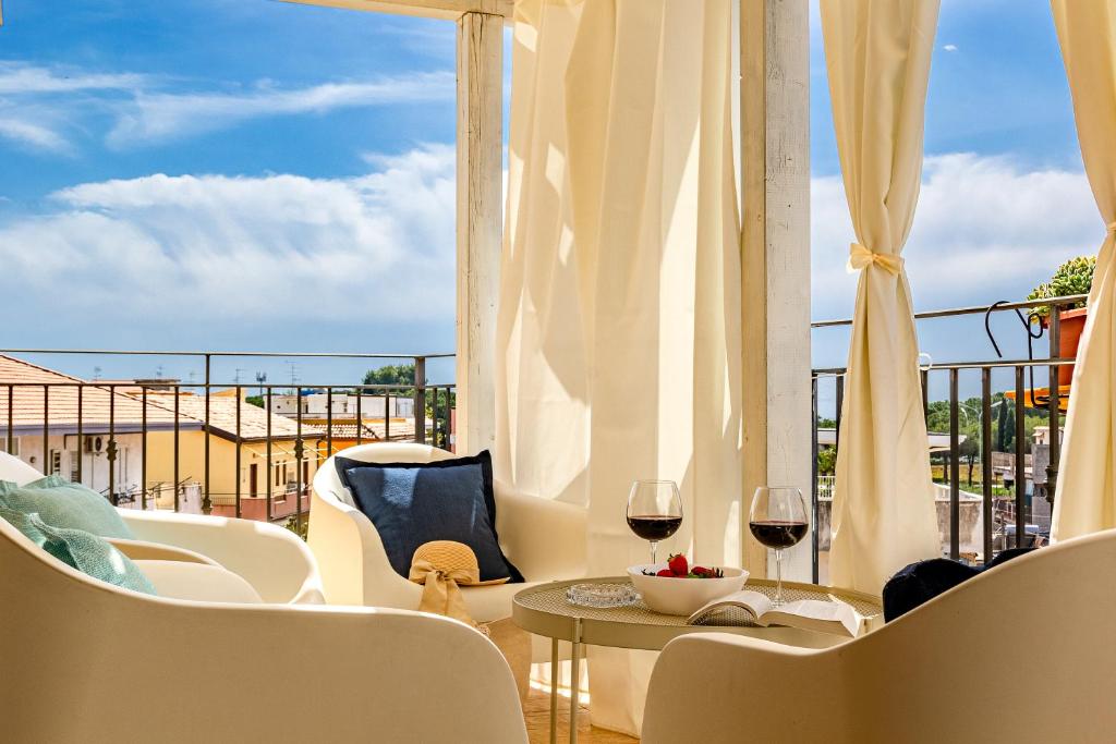 a balcony with a table and two glasses of wine at Villetta Desiderio Apartment in Giardini Naxos
