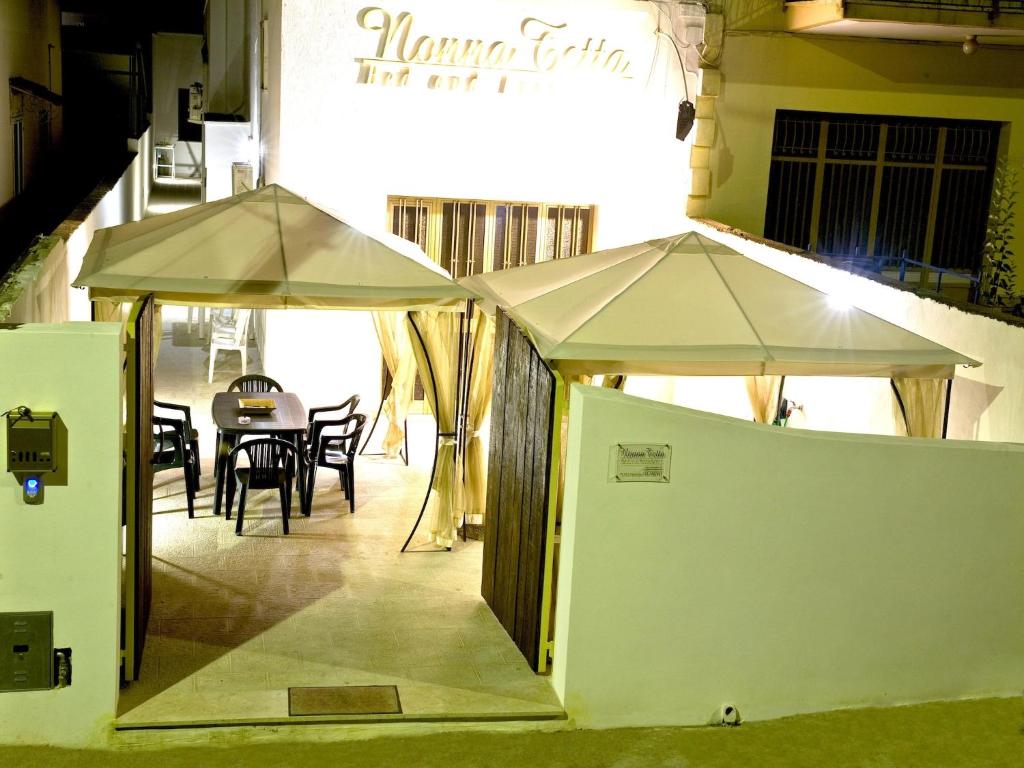Deux parasols blancs sont installés à l'extérieur d'un restaurant. dans l'établissement Casa vacanza Nonna Tetta, à Taurisano