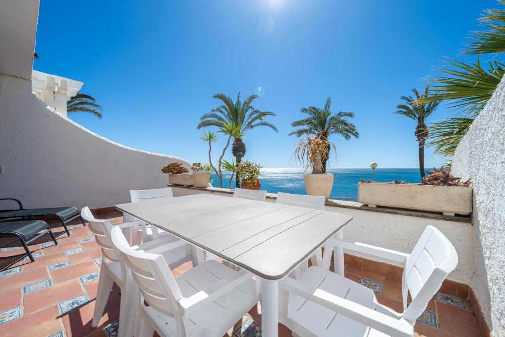 einen weißen Tisch und Stühle auf einer Terrasse mit Meerblick in der Unterkunft Hauzify I Casa Mirador in L'Ametlla de Mar