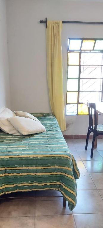 1 dormitorio con 1 cama, 1 silla y 1 ventana en San Andrés en Salta