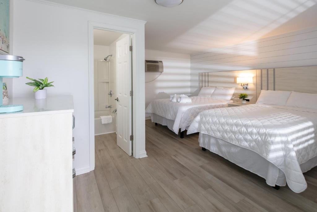 a white bedroom with two beds and a bathroom at Lily & Bloom in Myrtle Beach