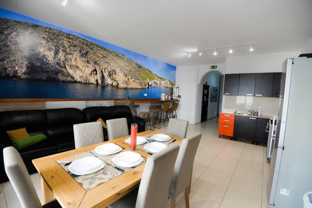 a kitchen and a dining room with a table and chairs at Seaside Xlendi apartment in Xlendi