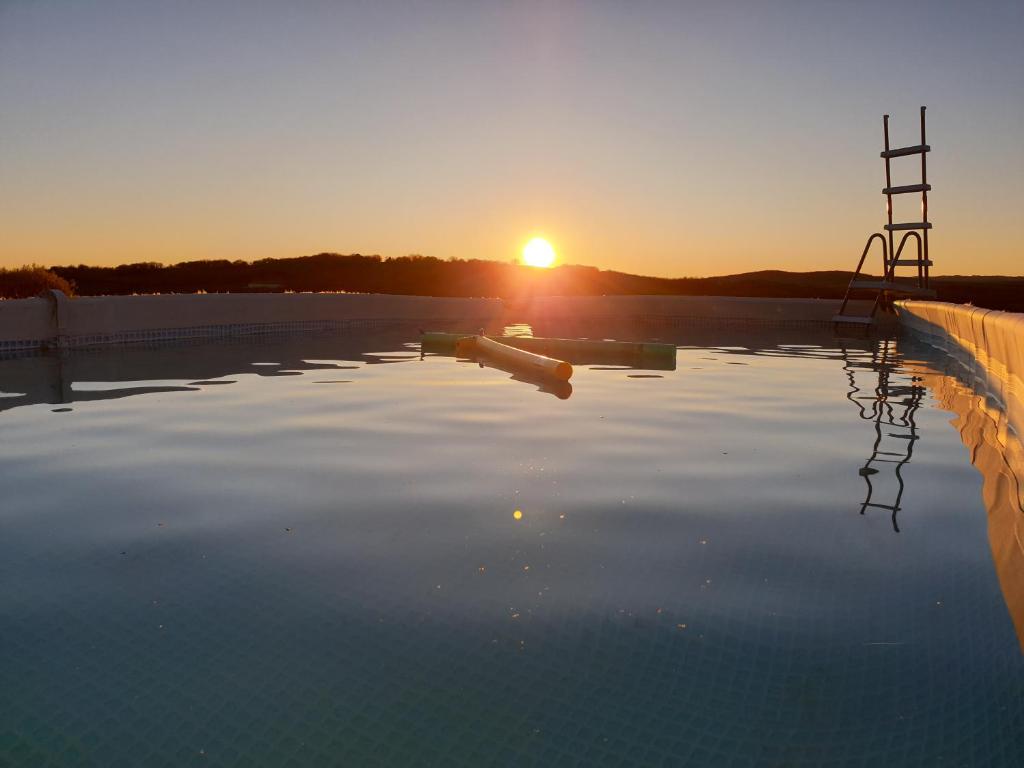a pool of water with the sunset in the background at Villa avec magnifique point de vue 14 Personnes 230 m2 in Blars