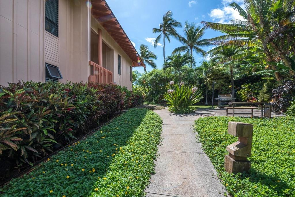 a walkway next to a building with palm trees at Kauai Makanui by Coldwell Banker Island Vacations in Koloa