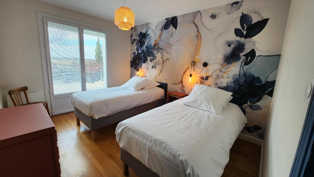 een slaapkamer met twee bedden en een schilderij aan de muur bij Le gîte du peintre in Entrains-sur-Nohain