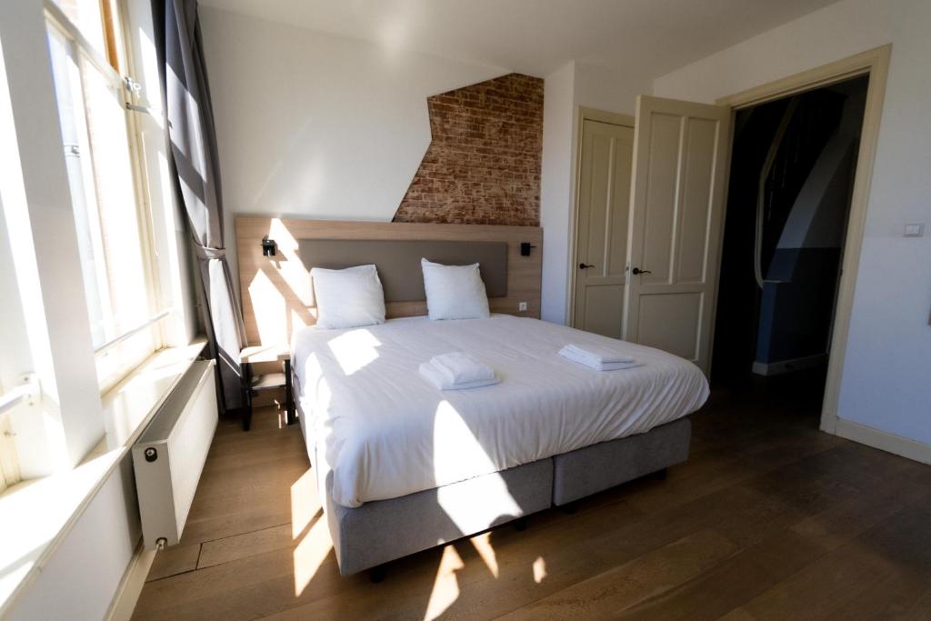 a bedroom with a bed with white sheets and pillows at Plantage Hortus Apartments in Amsterdam