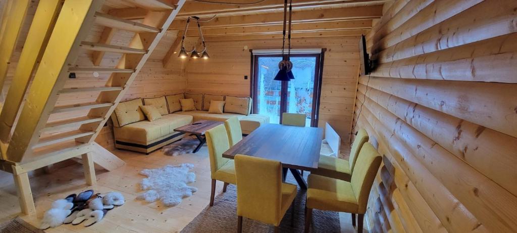 ein Esszimmer mit einem Tisch und Stühlen in einer Hütte in der Unterkunft Apartmani Prica in Crni Vrh