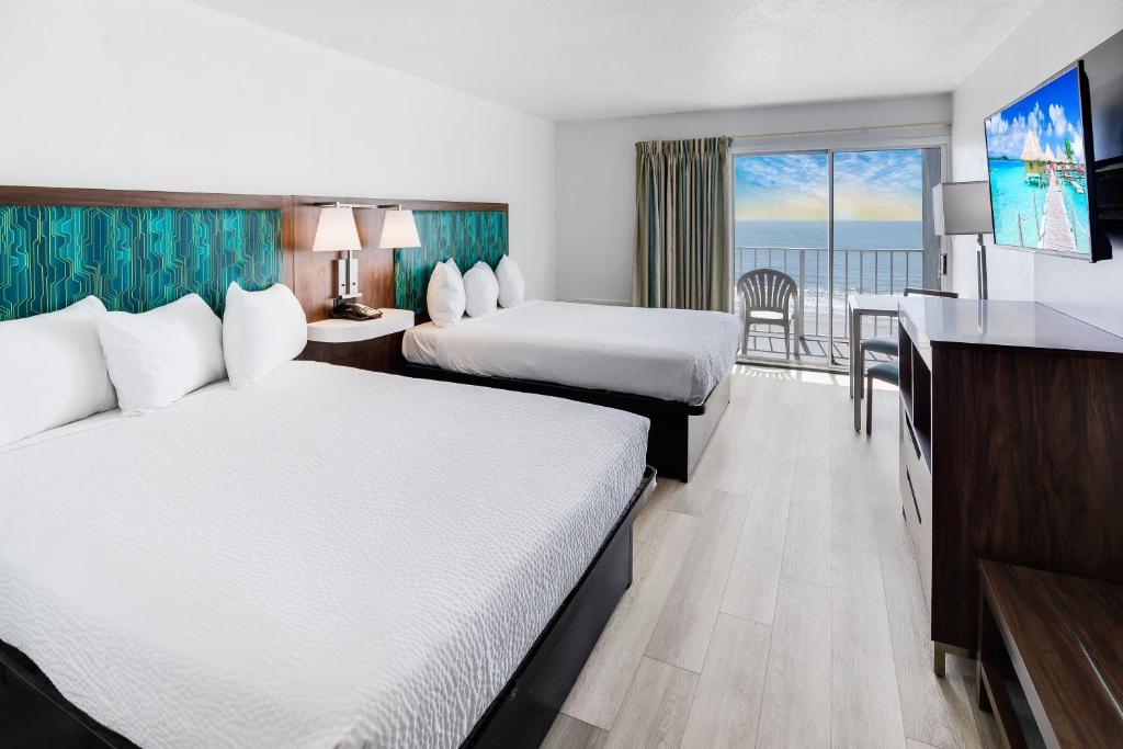 マートルビーチにあるBlu Atlantic Hotel & Suitesのベッド2台とバルコニー付きのホテルの部屋