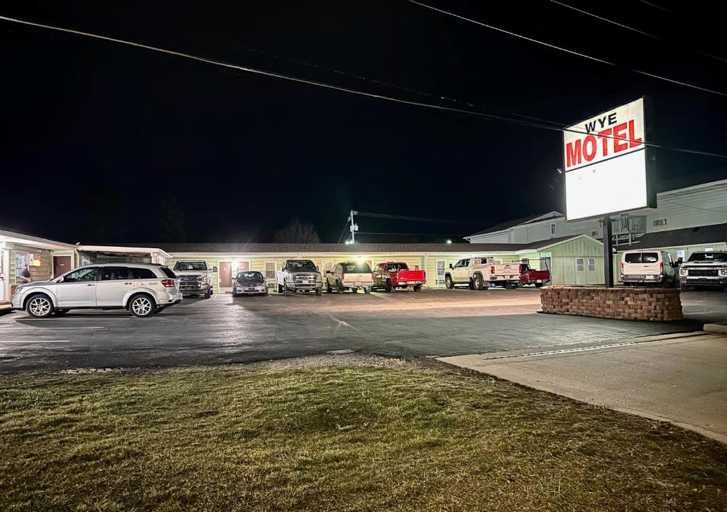 um motel com carros estacionados num parque de estacionamento à noite em Wye Motel em Clinton