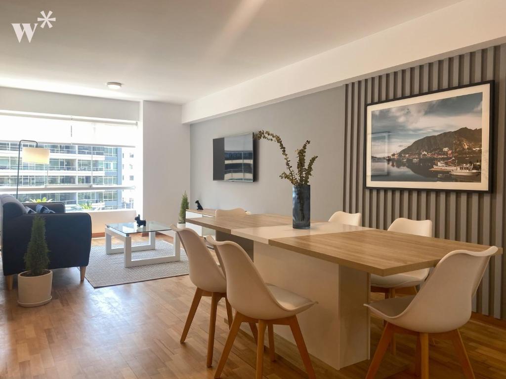 a dining room and living room with a wooden table and chairs at Classy 2BR in Miraflores in Lima