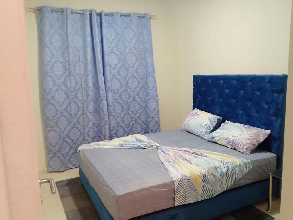 un lit avec une tête de lit bleue à côté d'une fenêtre dans l'établissement Taha home, à Casablanca