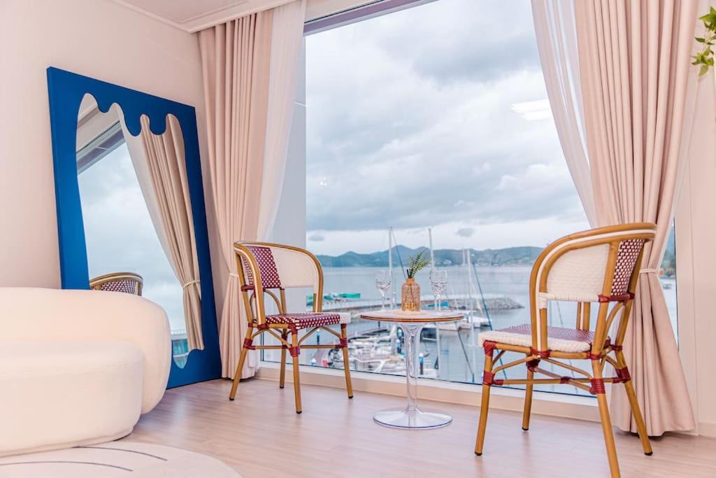 Zimmer mit einem Tisch und Stühlen sowie Blick auf das Wasser in der Unterkunft The castle ocean suite in Yeosu