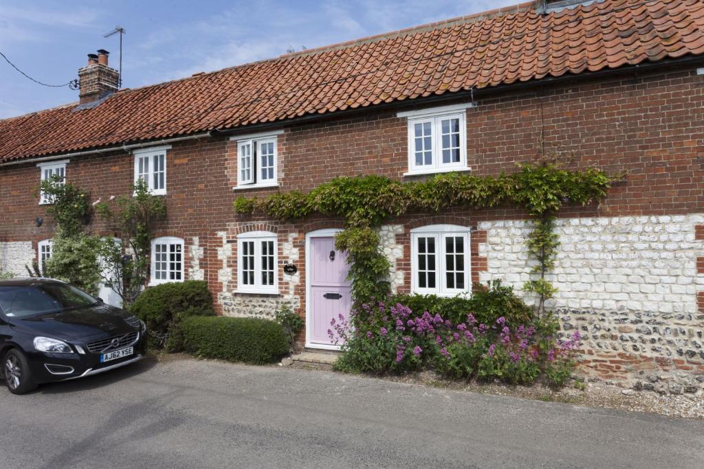 a brick house with a car parked in front of it at Rose Cottage in Burnham Thorpe
