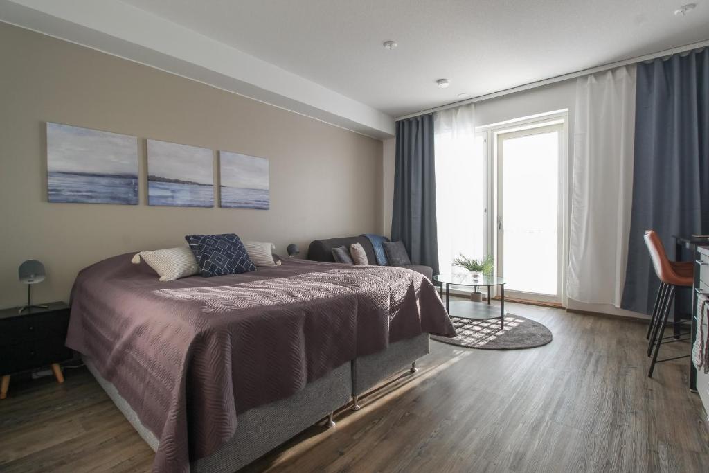 a bedroom with a bed and a chair and a window at Pramea Apartments Aapelintupa in Kuopio