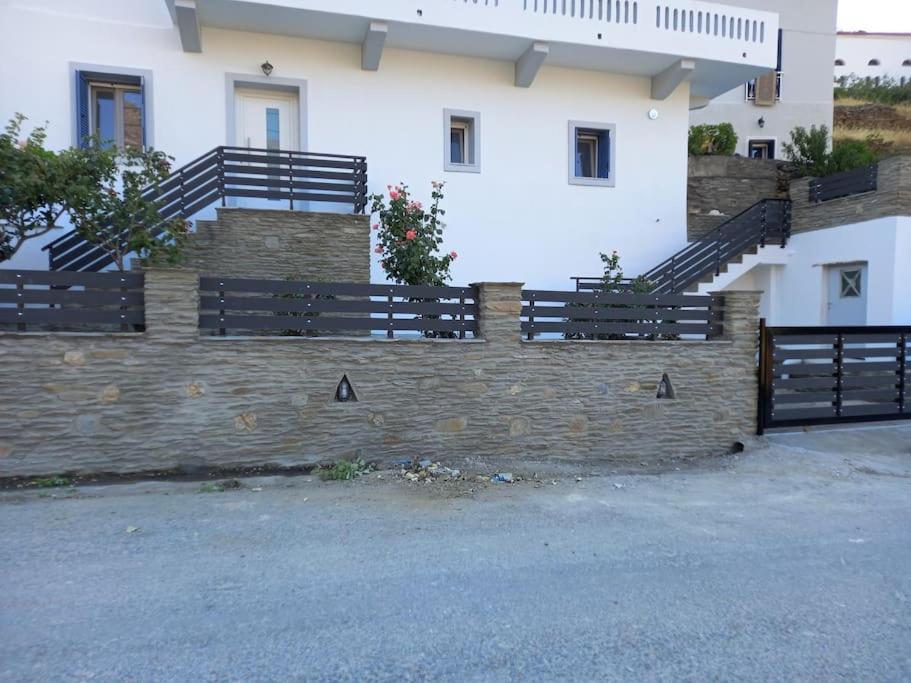 a fence in front of a building with stairs at Dipotamata House SynetI in Andros
