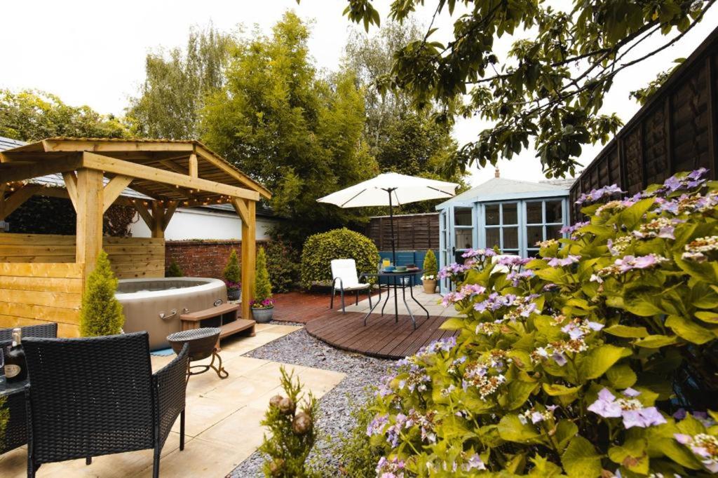 a garden with a hot tub and a pergola at Beval Cottage in Abergavenny