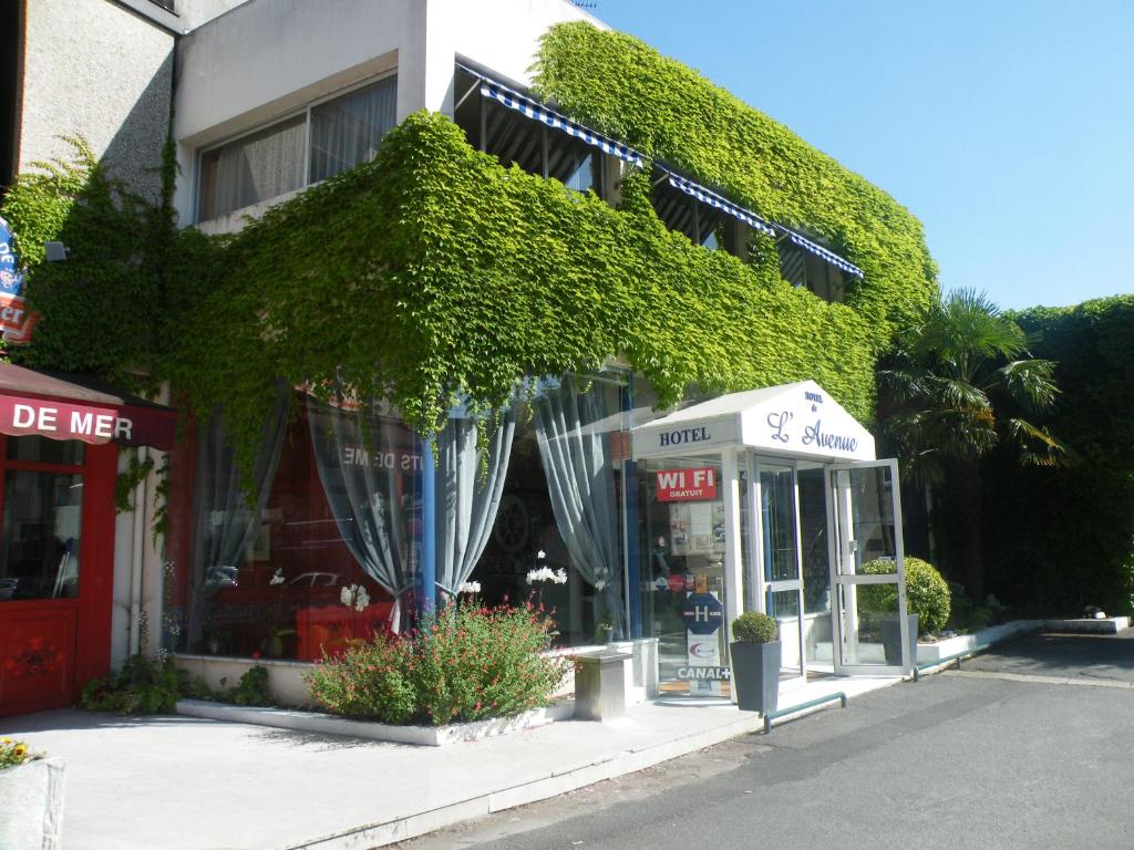 a store with ivy on the side of a building at Hôtel de L'Avenue in Saintes