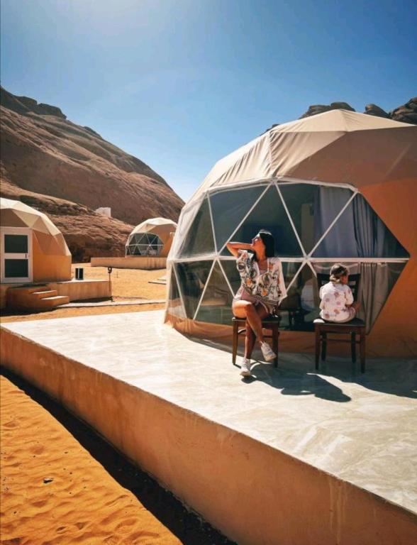 a woman sitting in a tent in the desert at Lukasa camp Wadi Rum in Disah