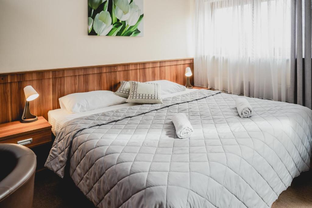 1 dormitorio con 1 cama grande con sábanas y almohadas blancas en Hotel nad morzem- Art-Pension, en Świerzno