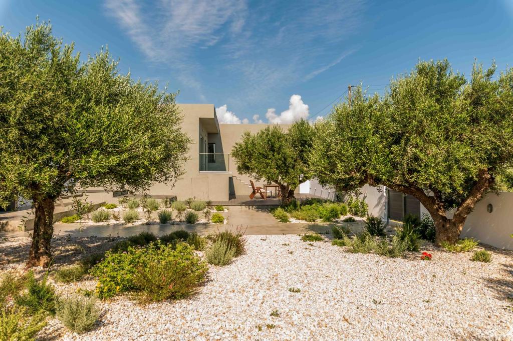 a house with trees in front of a building at Nama Villa 250m from the sea in Makry Gialos