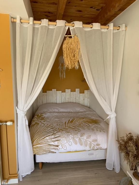 Chambre d’hôtes coconing في Brélès: غرفة نوم مع سرير المظلة مع الستائر