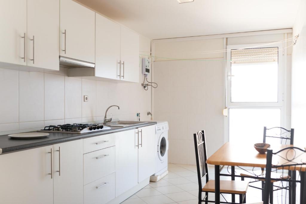 a kitchen with white cabinets and a table and a sink at 2 bdr cozy beachside apartment, Copacabana - LCGR in Mindelo