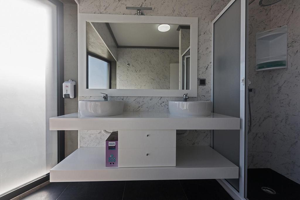La salle de bains est pourvue de 2 lavabos et d'un miroir. dans l'établissement Os Ninhos dos Avôs, à Ponta Delgada
