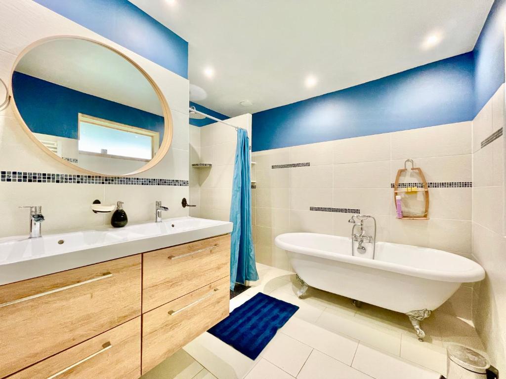 La salle de bains est pourvue d'une baignoire, d'un lavabo et d'un miroir. dans l'établissement Pop House - Grand Jardin clos - BBQ - Spacieux & Lumineux, à Saint-Nazaire