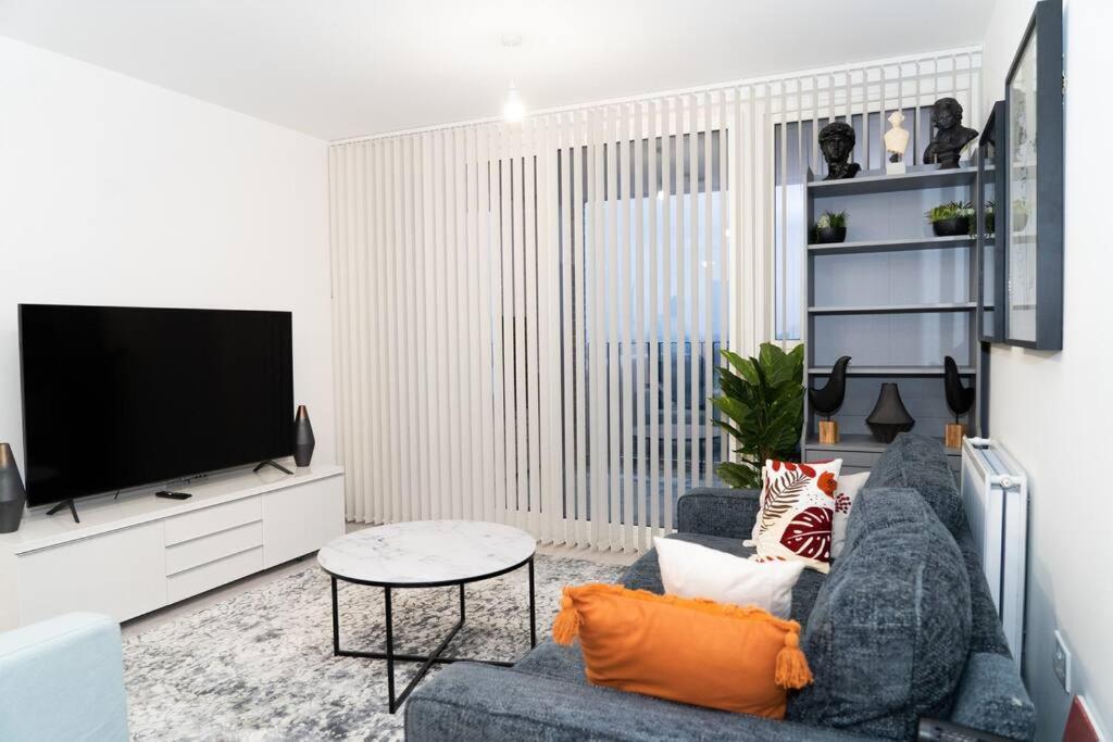 uma sala de estar com um sofá azul e uma televisão em Exquisite- stylish- luxurious 2 bed apartment em The Hyde