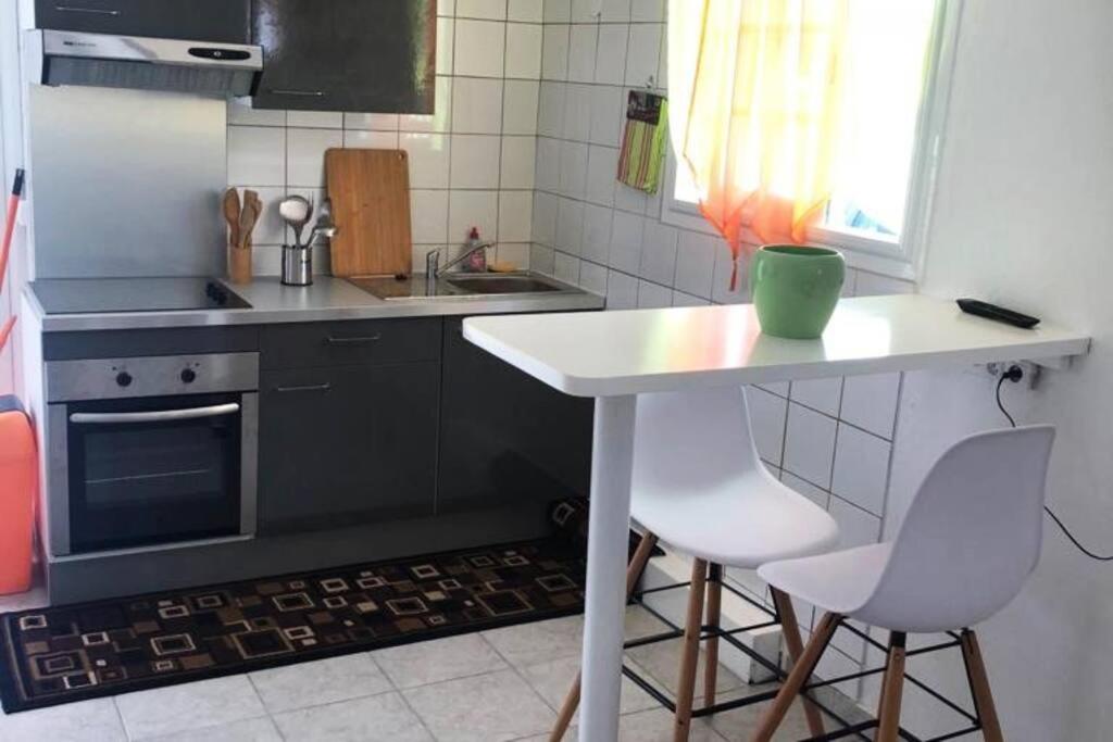 eine kleine Küche mit einem Tisch und 2 Stühlen in der Unterkunft Logement de 40m2 avec terrasse, moderne et équipé in Petit-Canal