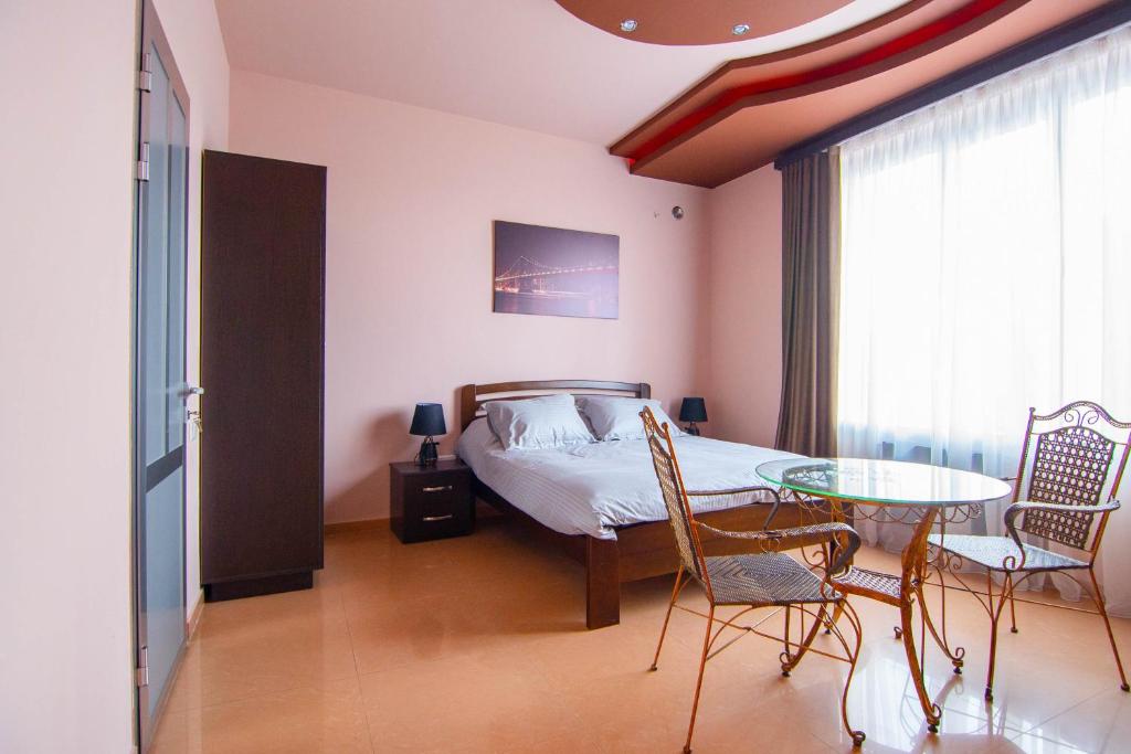 1 dormitorio con 1 cama, mesa y sillas en Mini Hotel Sovok, en Ereván