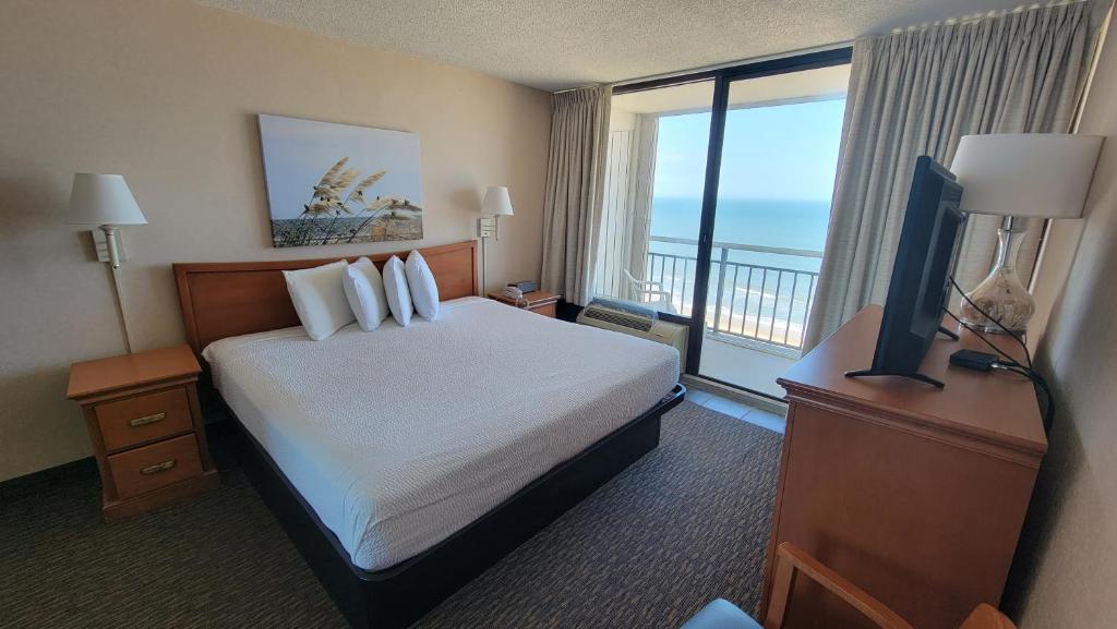 Four Sails Resort في فرجينيا بيتش: غرفة فندقية بسرير ونافذة كبيرة