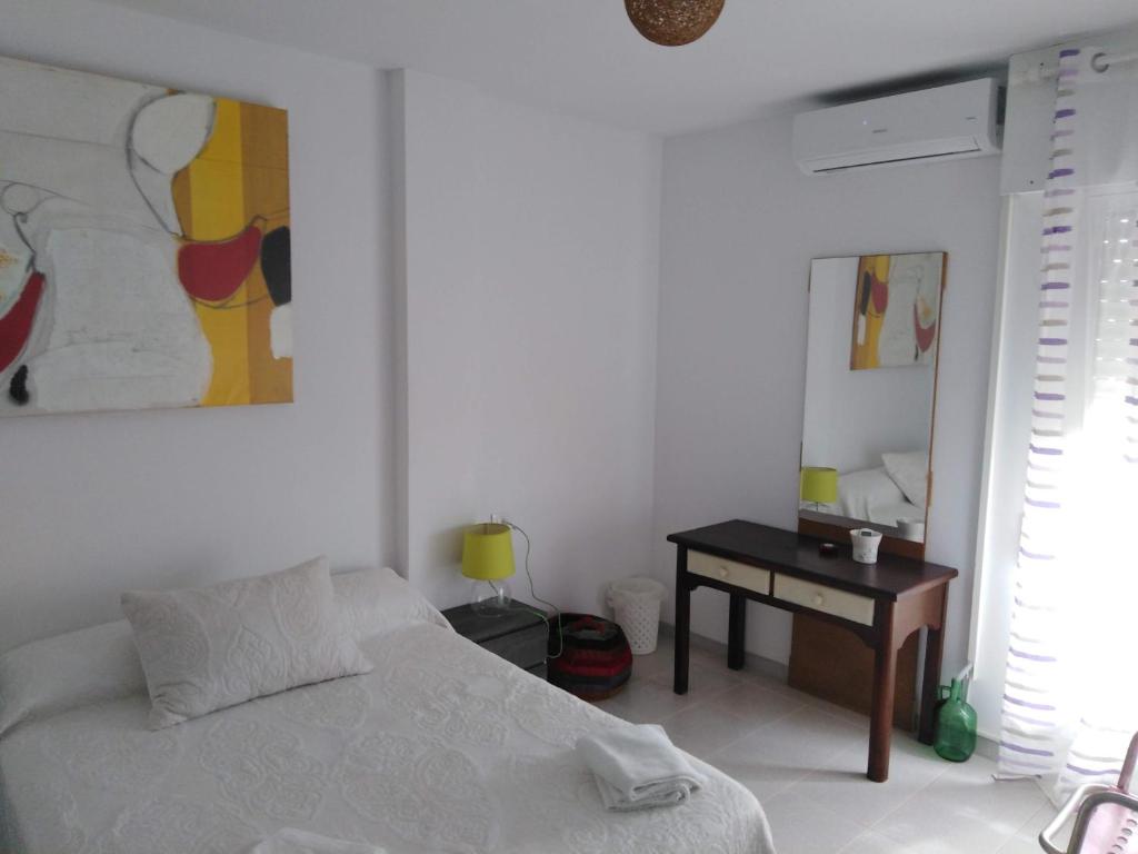 a white bedroom with a bed and a desk at PAUPET in Almería